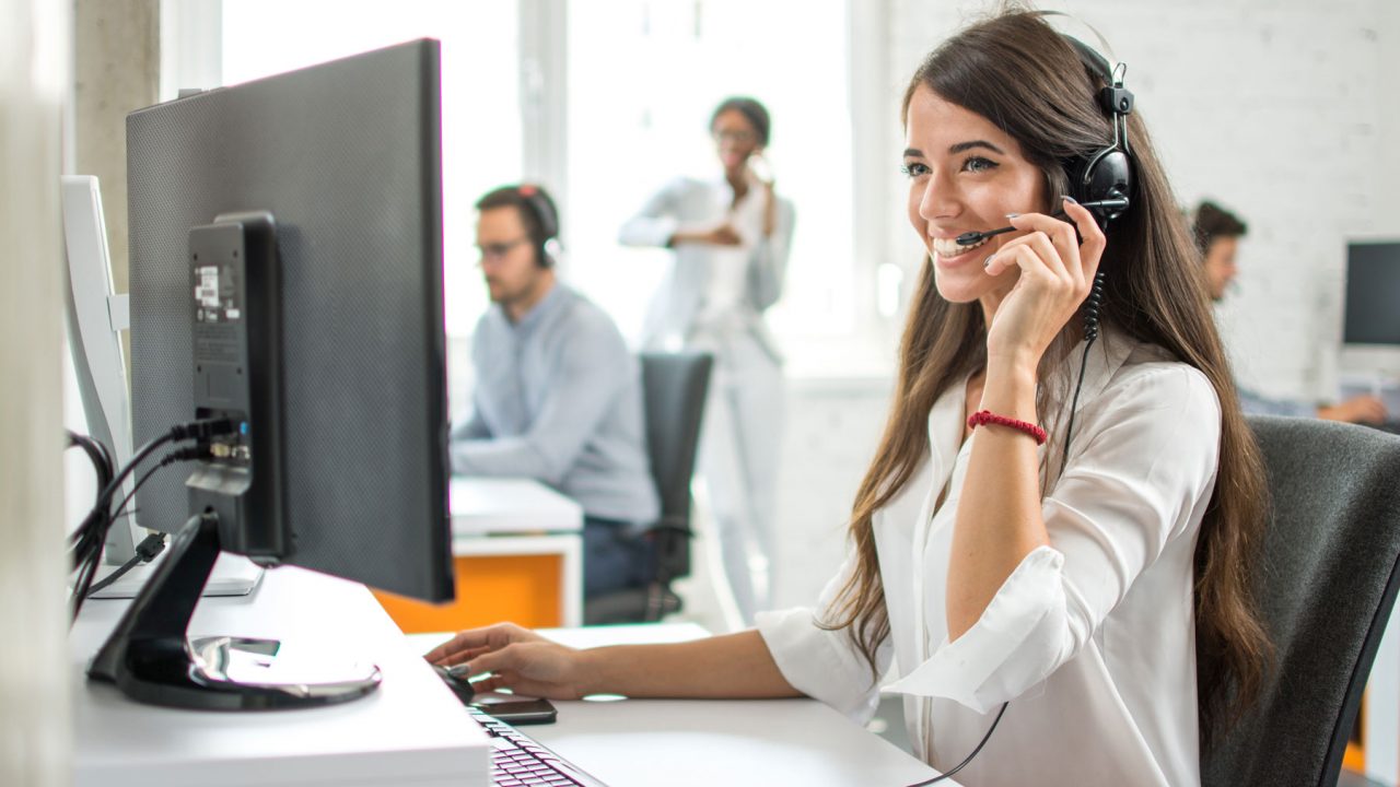 woman using a computer wearing a headset
