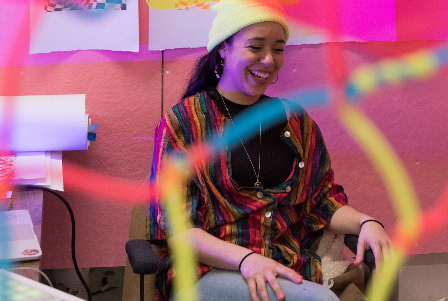 Young woman smiling during a moment in a bright, colorful environment.