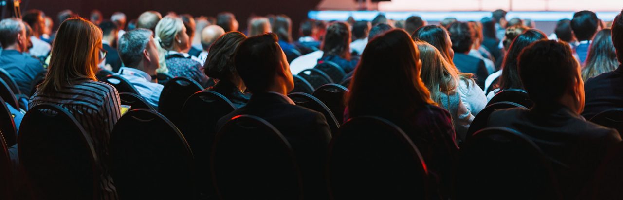 Back view of crowd seated during a live presentation or business conference.
