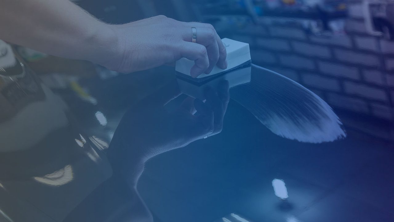 Close-up of hand applying coating to car surface, representing automotive ecommerce solutions.