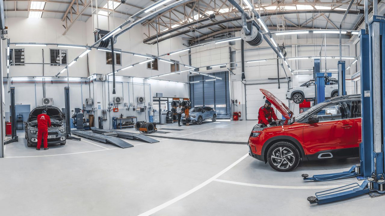 Mechanics working on vehicles in an automotive repair shop stocked with auto parts