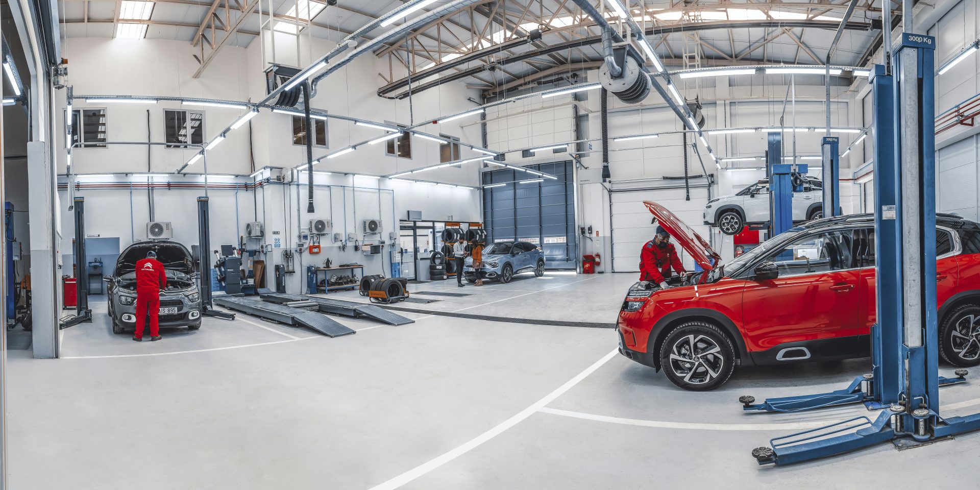 Mechanics working on vehicles in an automotive repair shop stocked with auto parts