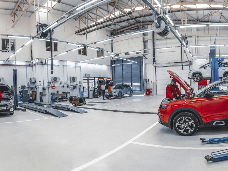 Mechanics working on vehicles in an automotive repair shop stocked with auto parts
