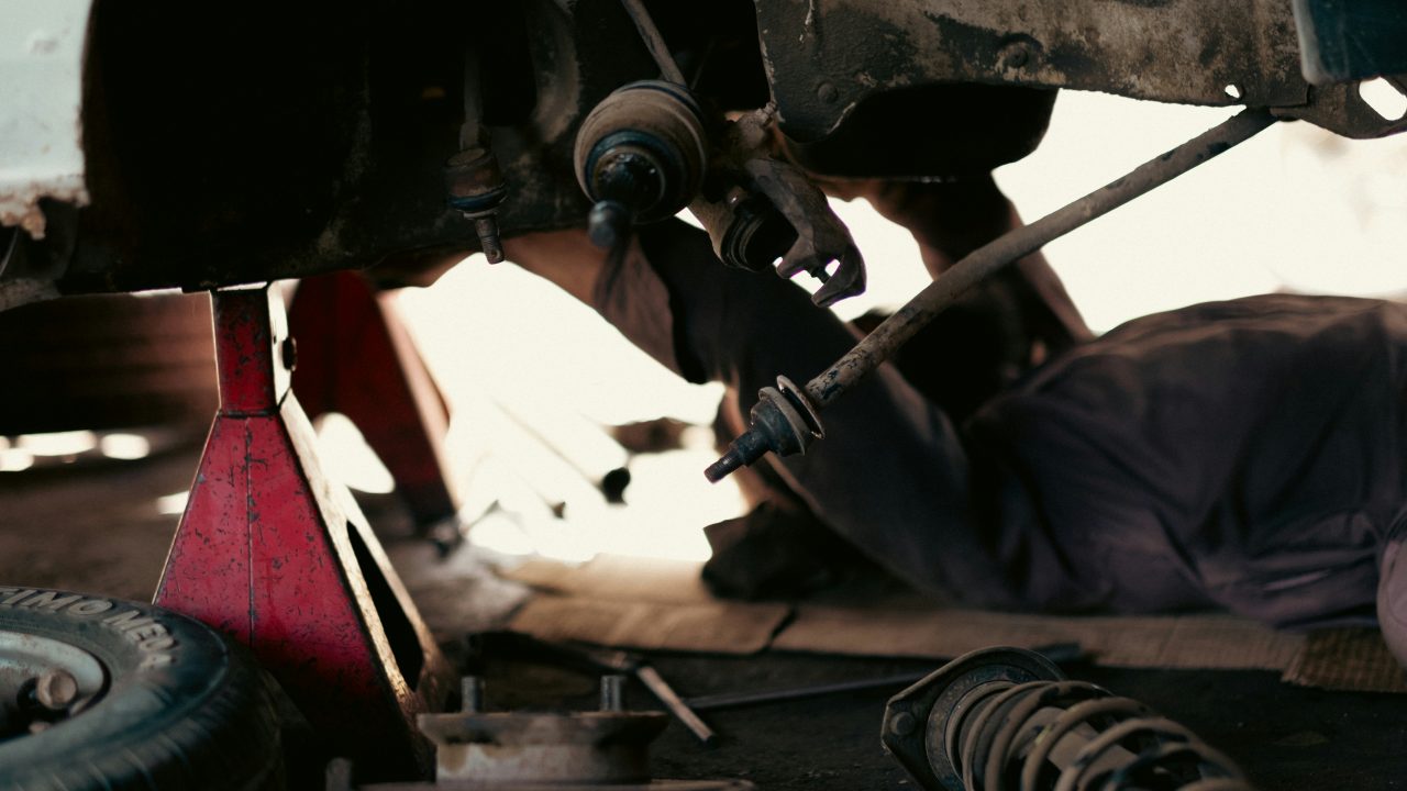 Mechanics working on vehicles in a busy automotive repair garage, representing parts and service that drive repeat purchases